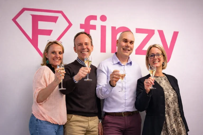L’équipe Finzy réunie devant le logo de l’entreprise.